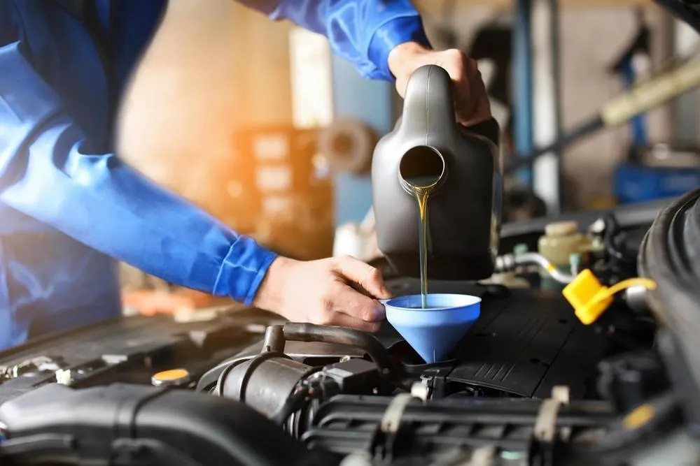 Männlicher Mechaniker füllt Autoöl im Servicecenter nach von B. Schmidt KFZ-Meisterbetrieb GmbH